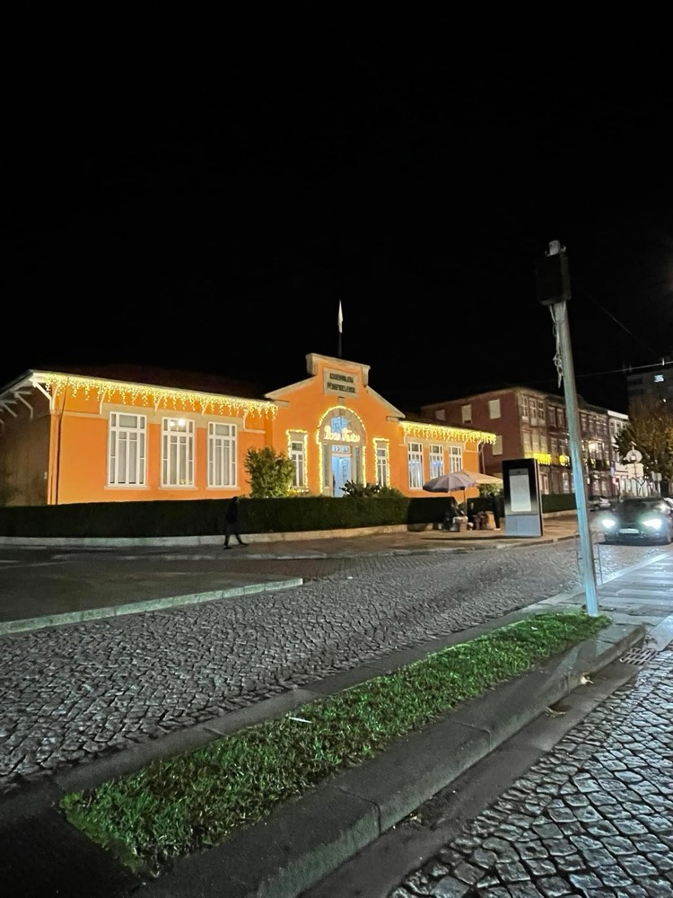 Edifício histórico cor de laranja com beirais, janelas e porta contornados por luzes de Natal